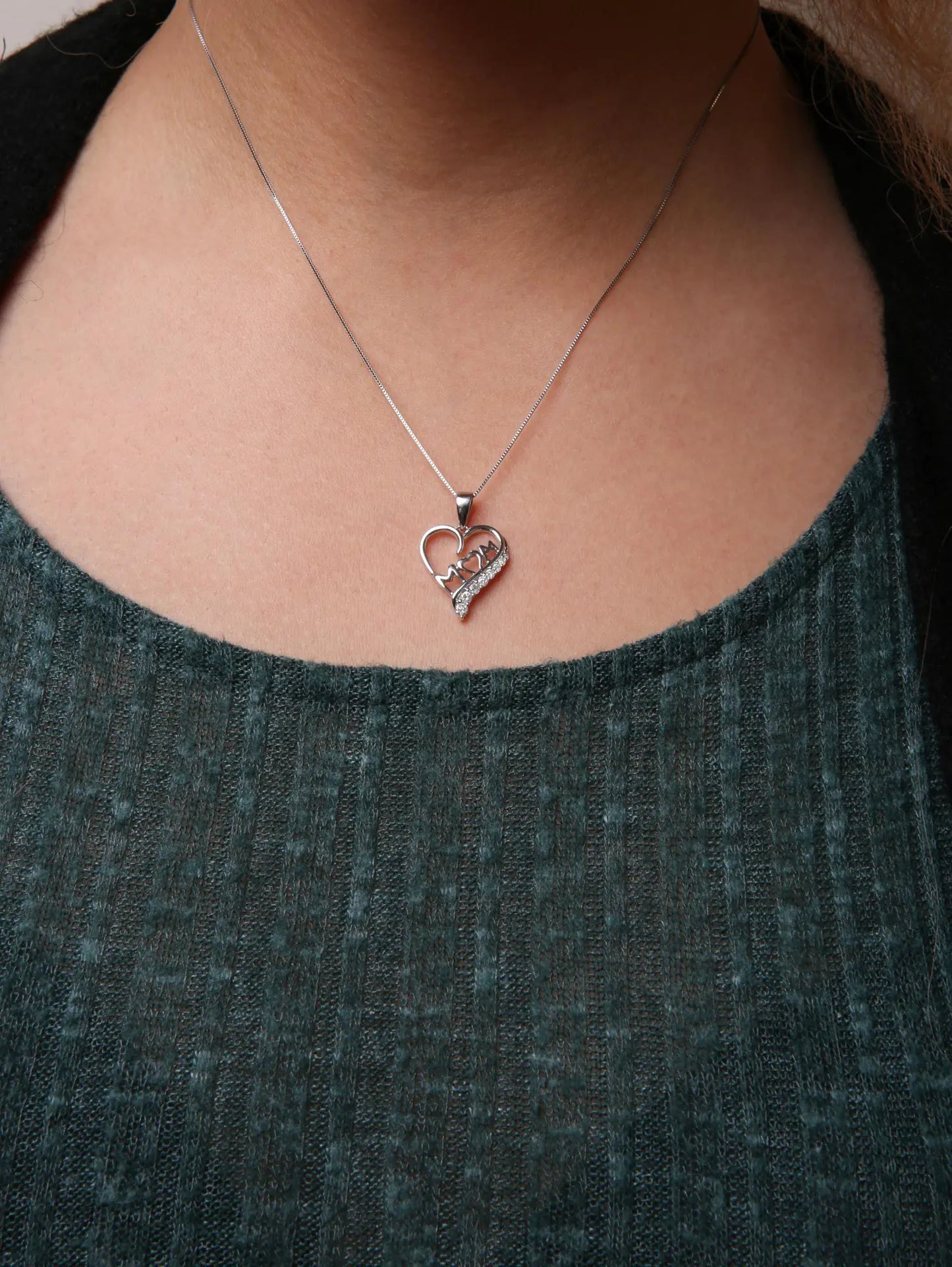 A woman wearing the 'Mom' and open heart pendant necklace, beautifully displayed as a sentimental gift for mom around her neck.